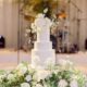 White wedding cake with sugar flower topper on a bed of fresh flowers
