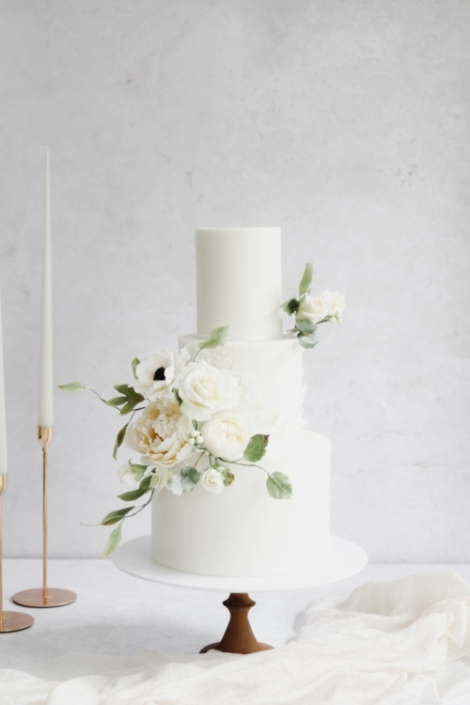 White wedding cake with lace detail and romantic white sugar flowers