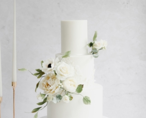 White wedding cake with lace detail and romantic white sugar flowers