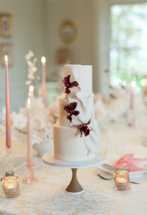 Blush wedding cake with fondant fabric texture and burgundy sugar flowers