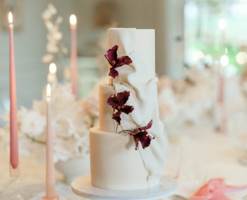 Blush wedding cake with fondant fabric texture and burgundy sugar flowers