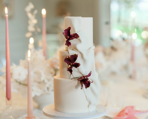 Blush wedding cake with fondant fabric texture and burgundy sugar flowers