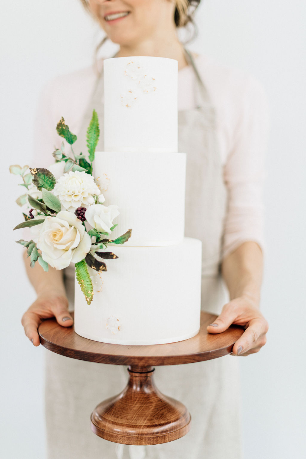 Baker holding decorated white wedding cake